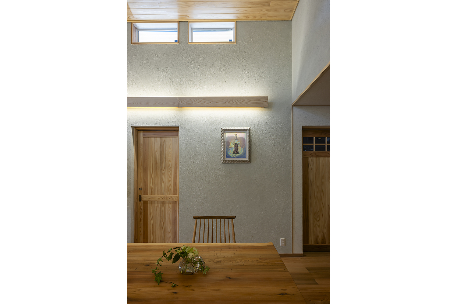 壁面の間接照明と高窓の光が調和する、落ち着いた明るさの室内。