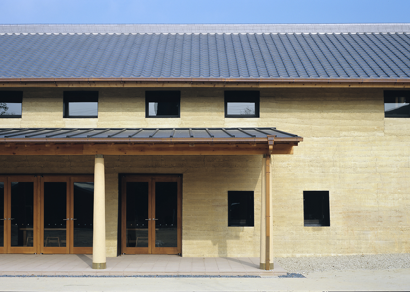 伝統技法「版築」による厚い外壁。内側へ傾け存在感を演出。