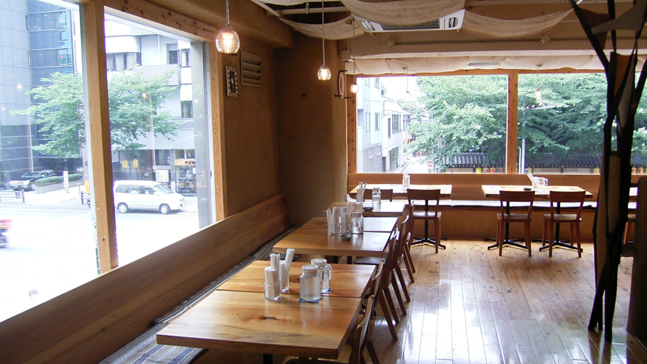 土壁と木のテーブルで構成された温かい食空間。
自然素材が料理を主役として際立たせるミニマルな内装。